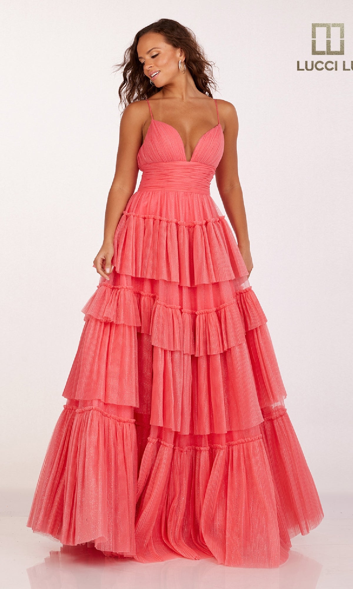 A woman models the Lucci Lu 1357 Tiered Ruffled Glitter Prom Dress, featuring a sleeveless deep V-neck and coral pink ruffled layers, standing against a plain light background.